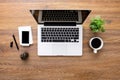 Wood office desk table with laptop computer, smartphone, cup of coffee and supplies. Top view, flat lay Royalty Free Stock Photo