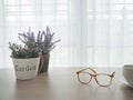 wood office table with beautiful variety flower on pot and modern eyeglasses, white ceramic coffee cup on blurry beautiful white