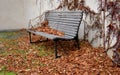 Wood-paneled benches by a bright plaster wall in a park sunk with leaves and creepers other clean and tidy around. cubes paving gr