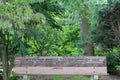 A wood park bench engraved with a quote from Sigmund Frued in front of a forested area in Janesville, Wisconsin