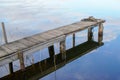 Wood pier ponton wooden jetty in blue water reflection mirror image sky and clouds Royalty Free Stock Photo