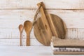 Wood round cutting board, spoons, stack of linen kitchen towels on white plank wood background Royalty Free Stock Photo