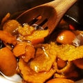 Wood slotted spoon stirring orange rinds in brown sugar making homemade simple syrup