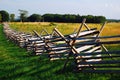A wood split rail fence cuts through a field