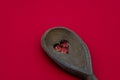 Wood spoon with a heart shaped hole filled with fish oil pills isolated on red background. Concept of cooking and health Royalty Free Stock Photo