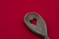 Wood spoon with a heart shaped hole isolated on a red background. Concept of cooking and health Royalty Free Stock Photo