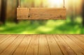 Wood table with hanging wooden sign on green forest blurred background Royalty Free Stock Photo