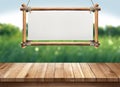 Wood table with hanging wooden sign on green nature blurred background Royalty Free Stock Photo
