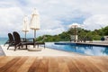 Wood table top on Beach chair in outdoor with swimming pool and Royalty Free Stock Photo