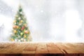 Wood table top on blur Christmas tree in snowfall background Royalty Free Stock Photo