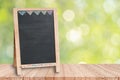 Wood table top on blur green background of trees in the park with blank blackboard Royalty Free Stock Photo