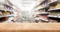 Wood table top on blur of supermarket product shelf background.