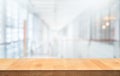 Wood table top on blur white glass wall background form office building