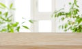 Wood table top on blur window and green plants background