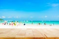 Wood table top on blurred beach background with people in colorful clothes Royalty Free Stock Photo