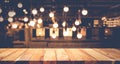 Wood table top on blurred of counter cafe shop with light bulb background Royalty Free Stock Photo