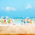 Wood table top with blurred people at the beach as background Royalty Free Stock Photo