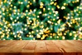 Wood table top with bokeh from decorative light on christmas tree in background Royalty Free Stock Photo