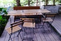 Wood tables and chairs in the park on the wood flooring with green plants in the background. Royalty Free Stock Photo