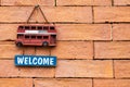Wood welcome sign hanging on old red brick wall background