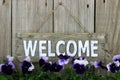 Wood welcome sign with purple flowers (pansies)