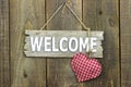 Wood welcome sign with red heart hanging on rustic wooden background