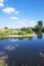 Wood and white clouds in the blue sky reflected in the mirrored water Royalty Free Stock Photo