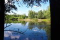 Wood and white clouds in the blue sky reflected in the mirrored water Royalty Free Stock Photo