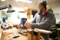 Wood worker building guitar in his shop, using a plunge router