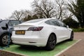 Woodbridge Suffolk UK February 20 2022: A Tesla Model 3 parked in a green parking bay using the public charging point to recharge