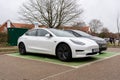 Woodbridge Suffolk UK February 20 2022: A Tesla Model 3 parked in a green parking bay using the public charging point to recharge