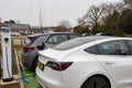 Woodbridge Suffolk UK February 20 2022: A Tesla Model 3 parked in a green parking bay using the public charging point to recharge