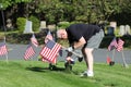 Volunteers placing an American Flag on the grave of a Military Veteran for Memorial Day