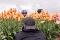 A photo of a man in a baseball hat with `O` sign laying on a tulip field