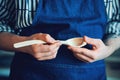 A woodcarver in a blue apron holds a delicate wooden spoon handmade. Cook`s kitchen utensils