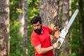 Woodcutter with chainsaw on sawmill. Illegal logging continues today. Lumberjack with chainsaw in his hands. Handsome Royalty Free Stock Photo