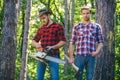 Woodcutters with chainsaw lumberjacks with axe. Hipsters men on serious face with axe. Lumberjack brutal and bearded