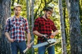 Woodcutters with chainsaw lumberjacks with axe. Hipsters men on serious face with axe. Lumberjack brutal and bearded