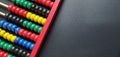 Wooden abacus. Red wooden frame with cross rods. Red, blue, yellow, green, black wooden elements. Math tool on a black background