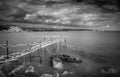 Wooden abandoned pier at sunset. Longexposure, with stormy cloudy sky. Royalty Free Stock Photo