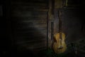 An wooden acoustic guitar is against a grunge textured wall. The room is dark with a spotlight for your copyspace Royalty Free Stock Photo