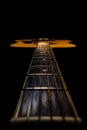 Wooden acoustic guitar with fretboard and strings over black studio background. Stringed plucked musical instrument