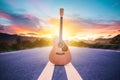 Wooden acoustic guitar lying on street with sunrise background