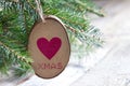 Wooden adornment with heart and xmas inscription hanging on christmas tree Royalty Free Stock Photo