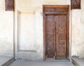 Wooden aged closed decorated door and beige plaster wall