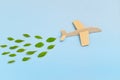 Wooden airplane model emitting fresh green leaves on blue background. Sustainable travel; clean and green energy; and biofuel Royalty Free Stock Photo