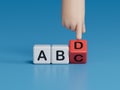 Wooden alphabet cube with words ABCD closeup and children hands on black background. Selective focus and education concept.