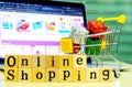 Wooden Alphabet `online shopping` and shopping cart with full of presents or gifts in front of the Blur Shopping Online Website on