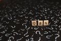 Wooden alphabet tiles with Q&A letter on black paper with QUESTION MARK