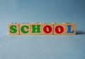 Wooden alphabet toy blocks with the text: school. Isolated kids multi-colored ABC cubes on blue background with copy space. Royalty Free Stock Photo